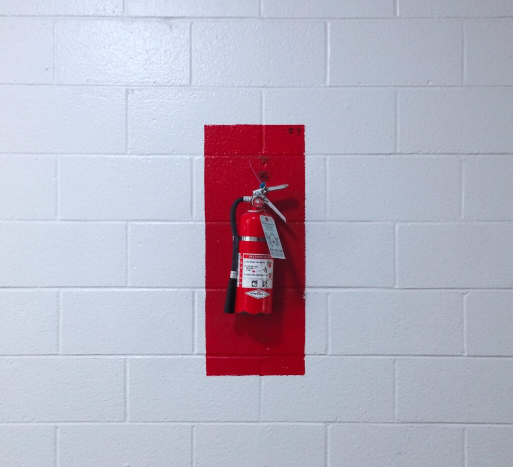 Fire extinguisher on cinderblock wall in a commercial building.