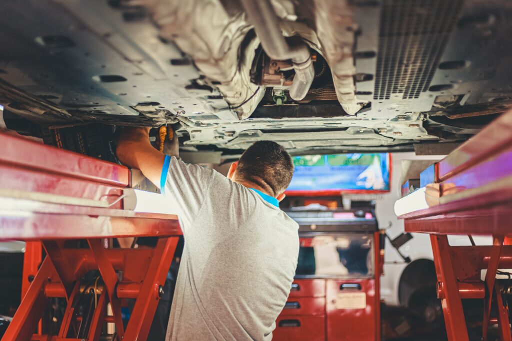 Mechanic under raised vehicle performing maintenance.